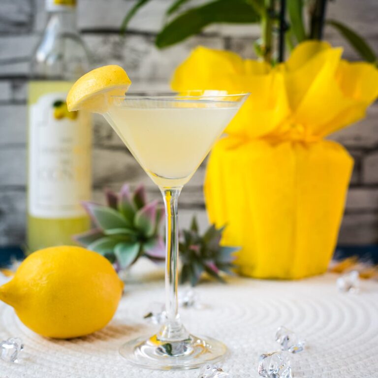 Gorgeous cocktail glass filled with a vibrant limoncello martini, garnished with a lemon wedge.