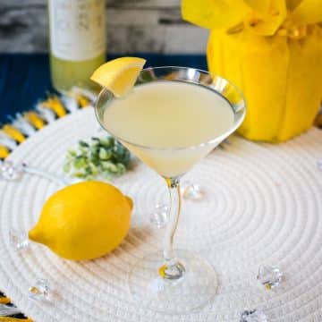 Gorgeous cocktail glass filled with a vibrant limoncello martini, garnished with a lemon wedge.