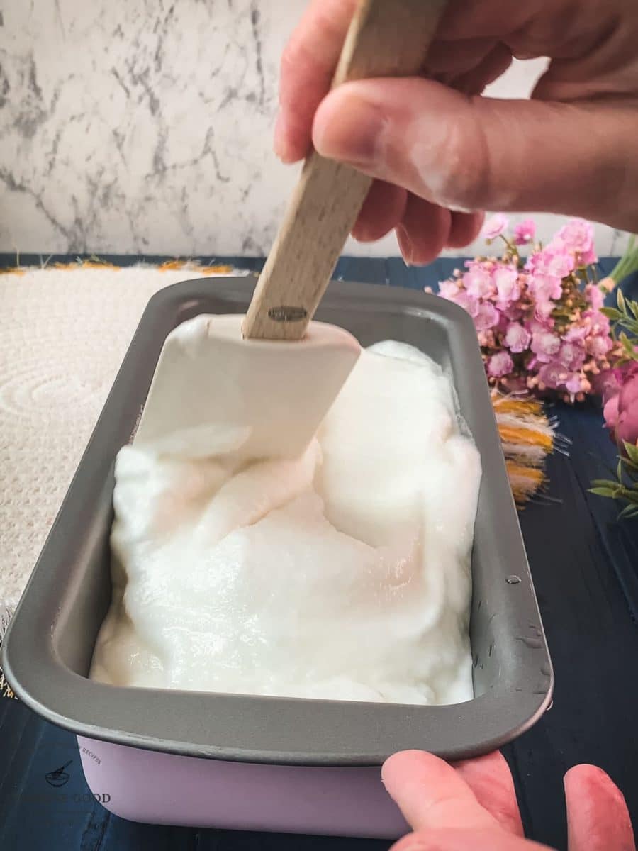 Spreading the finished lemon sorbet into an ice cream container.