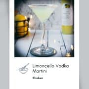 Gorgeous Limoncello vodka martini with orange sugar rim, placed on a mirrored coaster on a white wooden board.