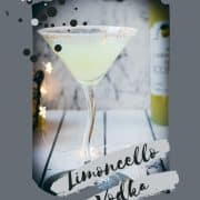 Gorgeous Limoncello vodka martini with orange sugar rim, placed on a mirrored coaster on a white wooden board.