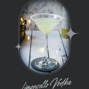 Gorgeous Limoncello vodka martini with orange sugar rim, placed on a mirrored coaster on a white wooden board.