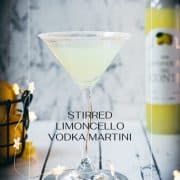 Gorgeous Limoncello vodka martini with orange sugar rim, placed on a mirrored coaster on a white wooden board.