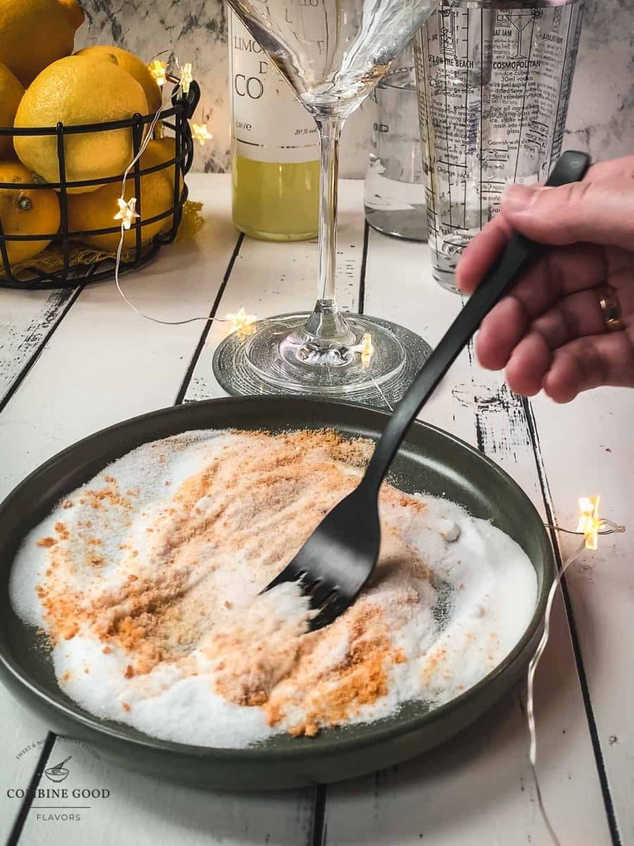 Using a fork, combine fine granulated sugar with organic orange zest on a plate.