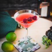 Delicious raspberry margarita served in cocktail glass and garnished with fresh raspberries on a cocktail spike.