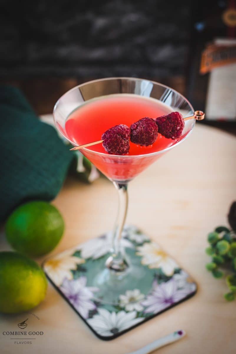 Delicious raspberry margarita served in cocktail glass and garnished with fresh raspberries on a cocktail pike.