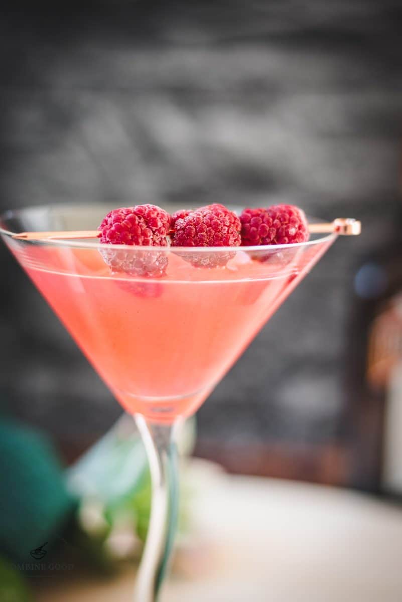 Delicious raspberry margarita served in cocktail glass and garnished with fresh raspberries on a cocktail pike.