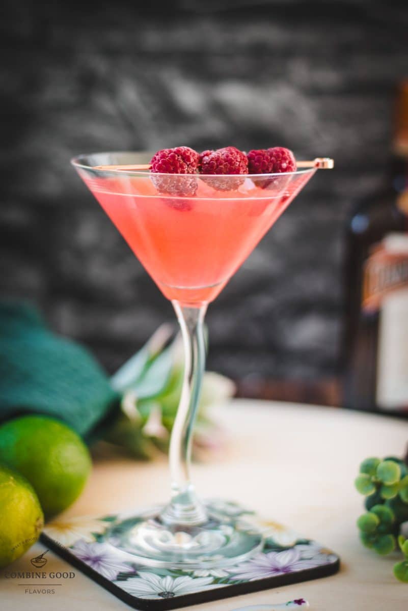 Delicious raspberry margarita served in cocktail glass and garnished with fresh raspberries on a cocktail pike.