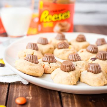 Utterly delicious Reese's peanut butter cookies served on a white plate, with a Reese's peanut butter mini cup on top.