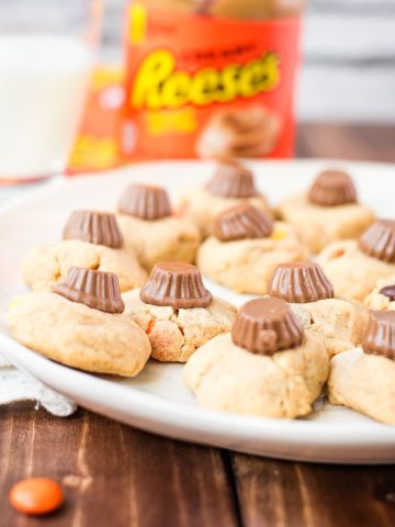 Utterly delicious Reese's peanut butter cookies served on a white plate, with a Reese's peanut butter mini cup on top.