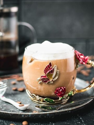 Delicious french press iced coffee served in gorgeous glass mug decorated with roses and butterflies.