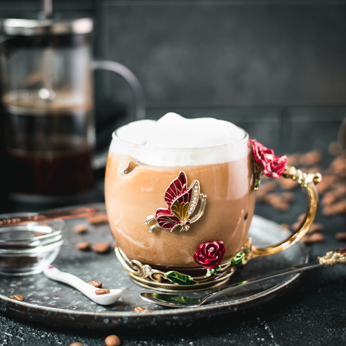 Delicious french press iced coffee served in gorgeous glass mug decorated with roses and butterflies.