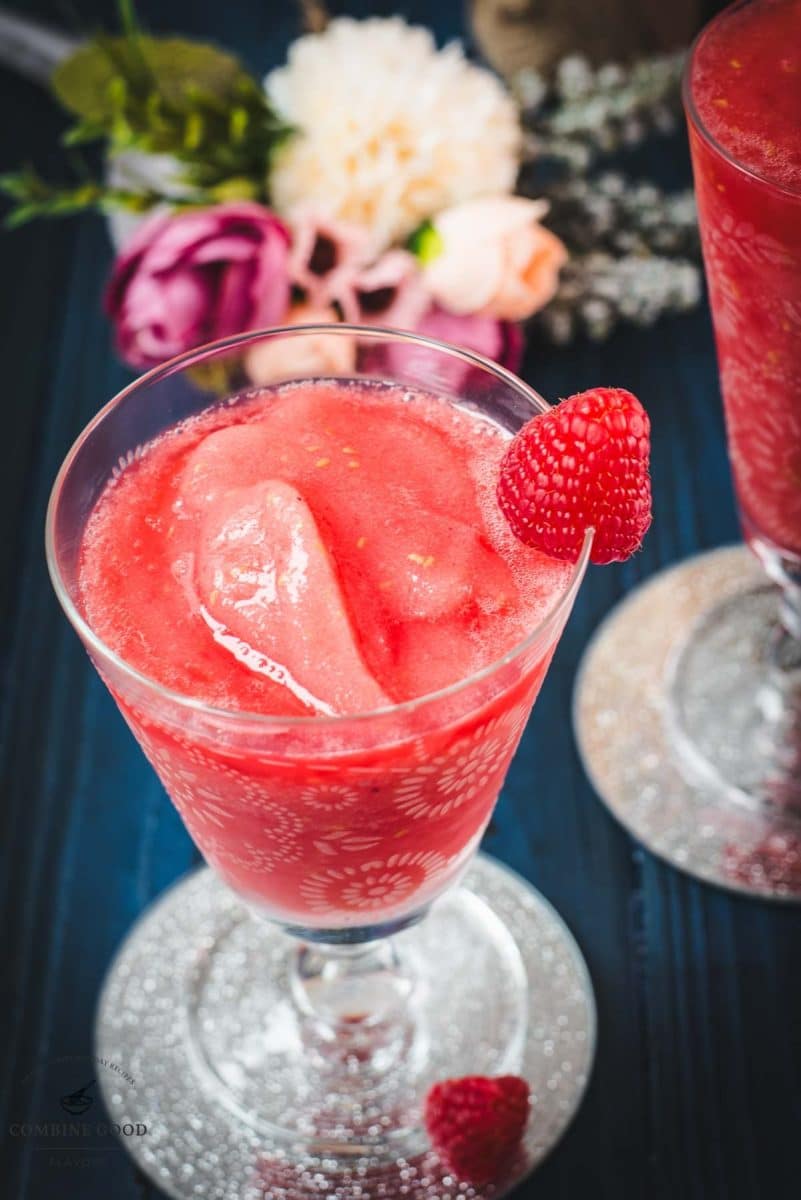 Two gorgeous glasses filled with a delicious frozen raspberry margarita cocktail, placed on glass coaster.