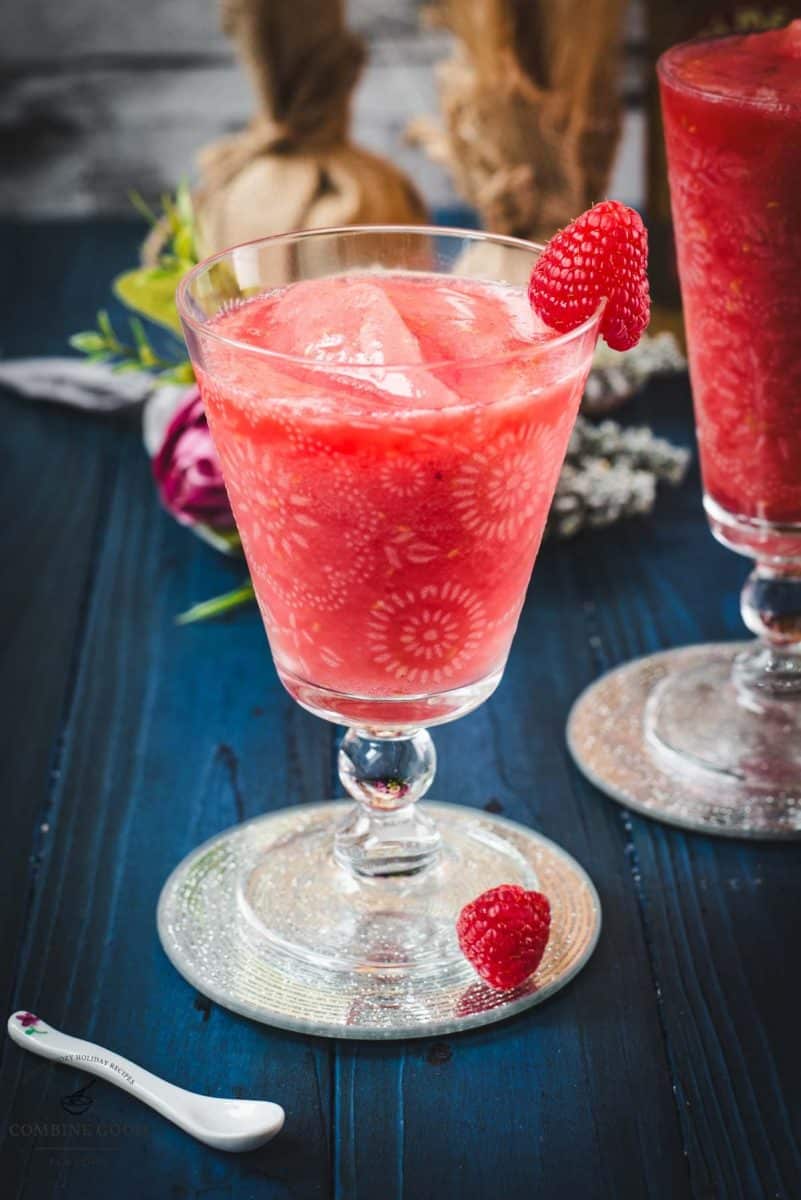 Two gorgeous glasses filled with a delicious frozen raspberry margarita cocktail, placed on glass coaster.