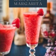 Two gorgeous glasses filled with a delicious frozen raspberry margarita cocktail, placed on glass coaster.