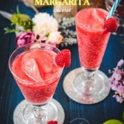 Two gorgeous glasses filled with a delicious frozen raspberry margarita cocktail, placed on glass coaster.