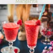 Two gorgeous glasses filled with a delicious frozen raspberry margarita cocktail, placed on glass coaster.