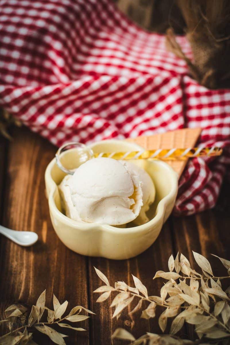 Delightful serving bowl filled with sour cream ice cream that looks like an ice cream cone with ice cream scoops. Placed on a brown wooden background.