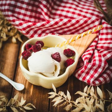 Delightful serving bowl filled with sour cream ice cream that looks like an ice cream cone with ice cream scoops. Placed on a brown wooden background.