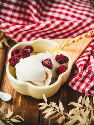 Delightful serving bowl filled with sour cream ice cream that looks like an ice cream cone with ice cream scoops. Placed on a brown wooden background.