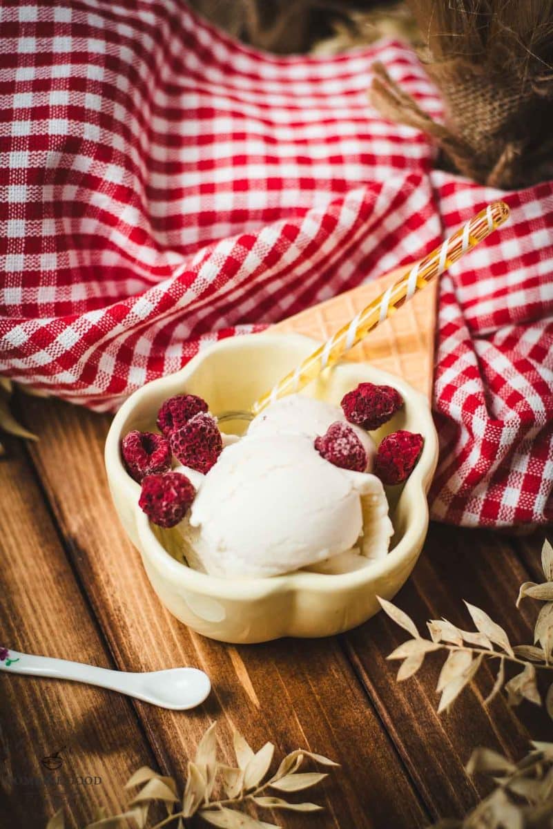 Delightful serving bowl filled with sour cream ice cream that looks like an ice cream cone with ice cream scoops. Placed on a brown wooden background.