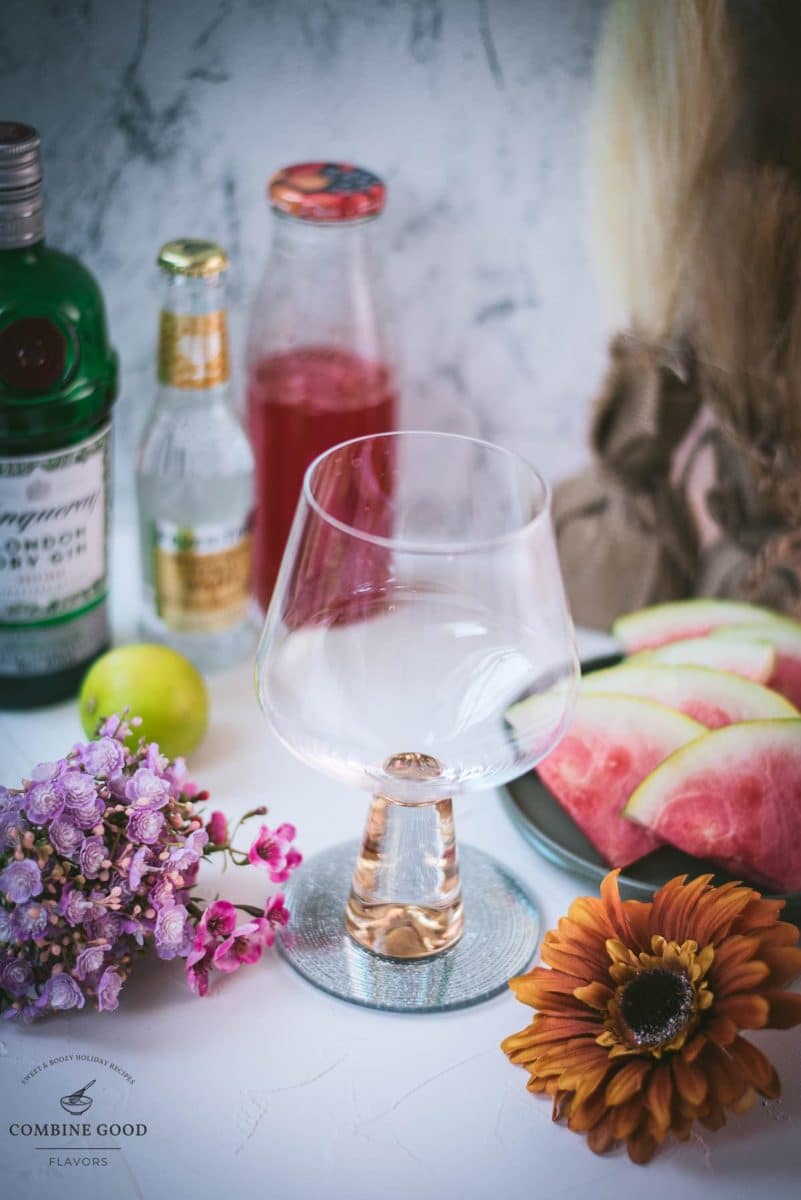 Ingredients for a watermelon gin and tonic: watermelon syrup, gin, cubed ice, and tonic water.