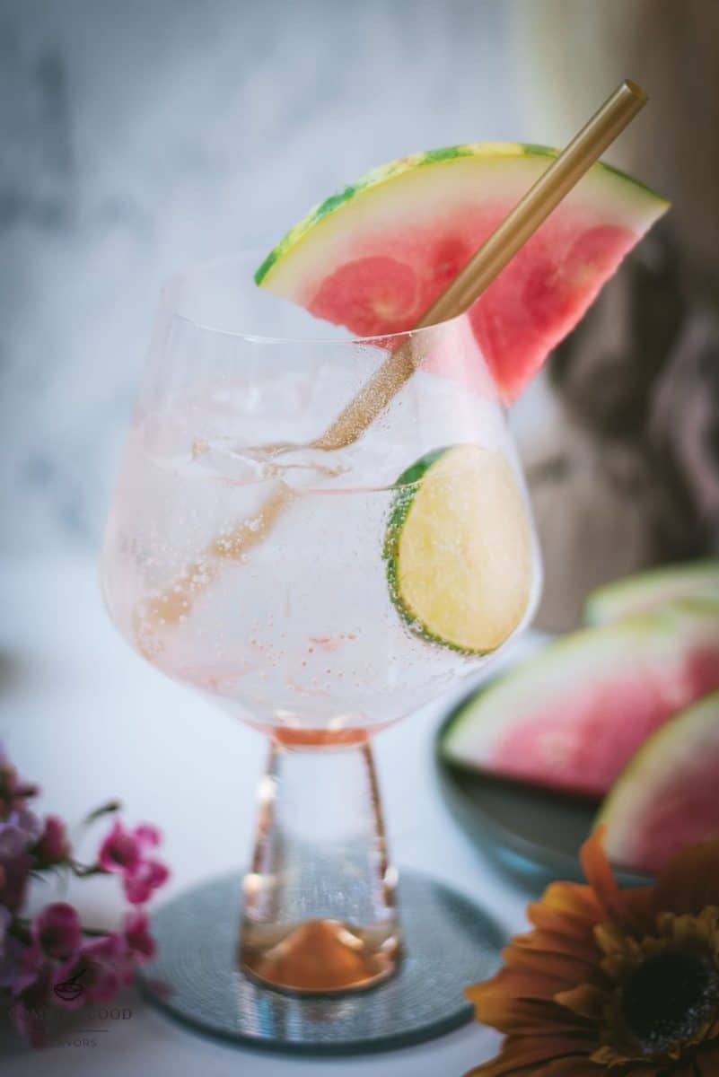 Beautiful balloon like glass filled with refreshing watermelon gin and tonic. Garnished with a reusable drinking straw, a big watermelon slice, and a lime slice.