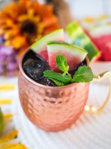 Gorgeous copper mug, filled with a delicious watermelon Moscow mule. Garnished with watermelon slices and mint leaves.