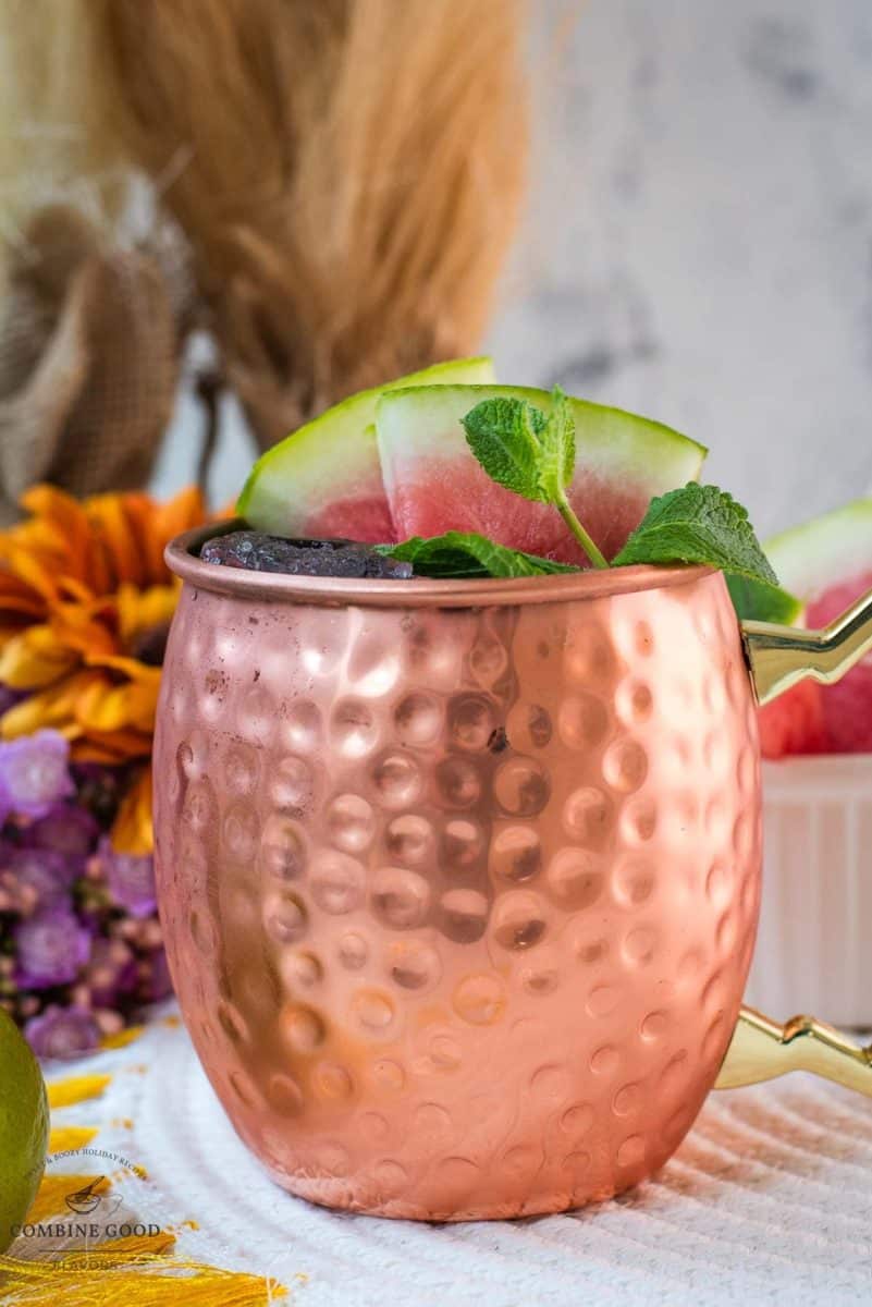 Gorgeous copper mug, filled with a delicious watermelon Moscow mule. Garnished with watermelon slices and mint leaves.