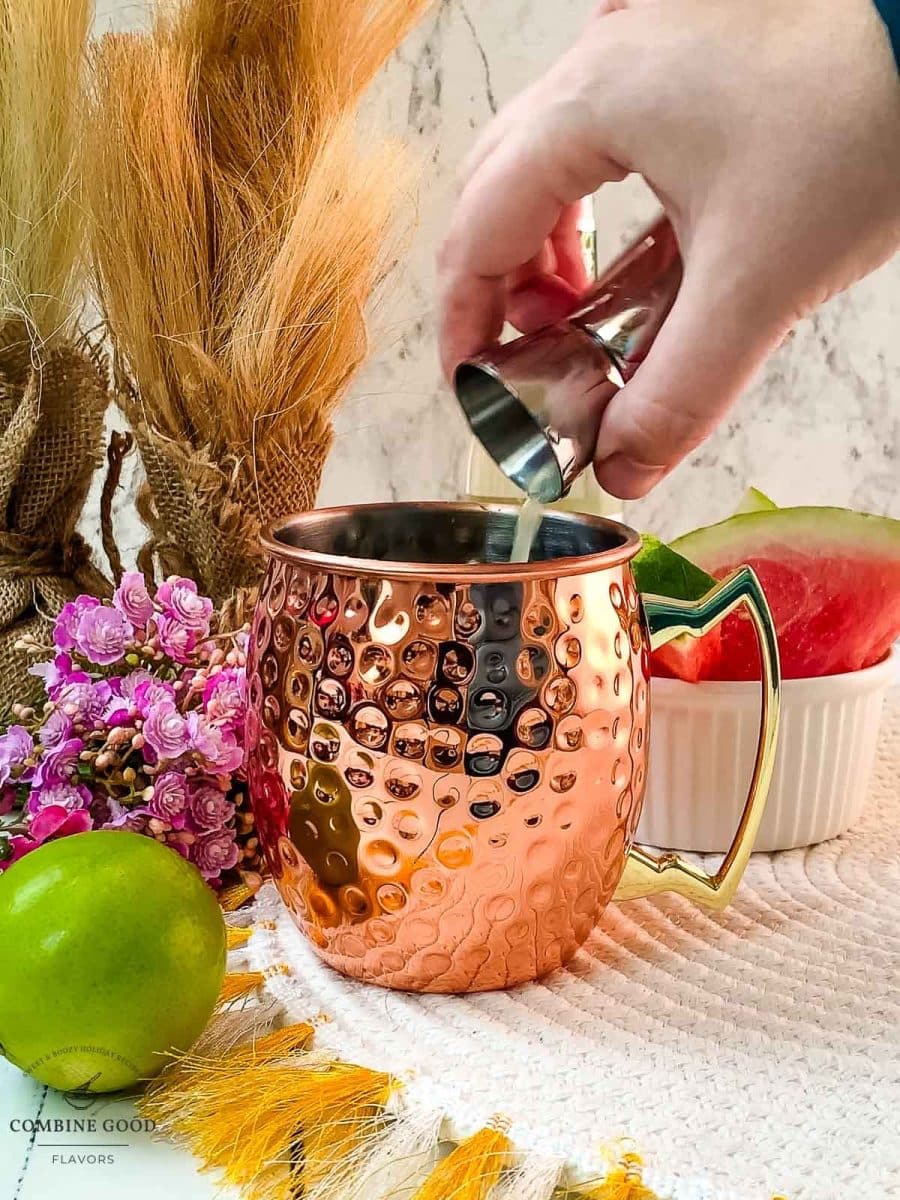 Adding lime juice to the copper mug.