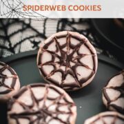 Hauntingly delicious spiderweb cookies, placed on black plate on spiderweb ground.