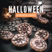 Hauntingly delicious spiderweb cookies, placed on black plate on spiderweb ground.