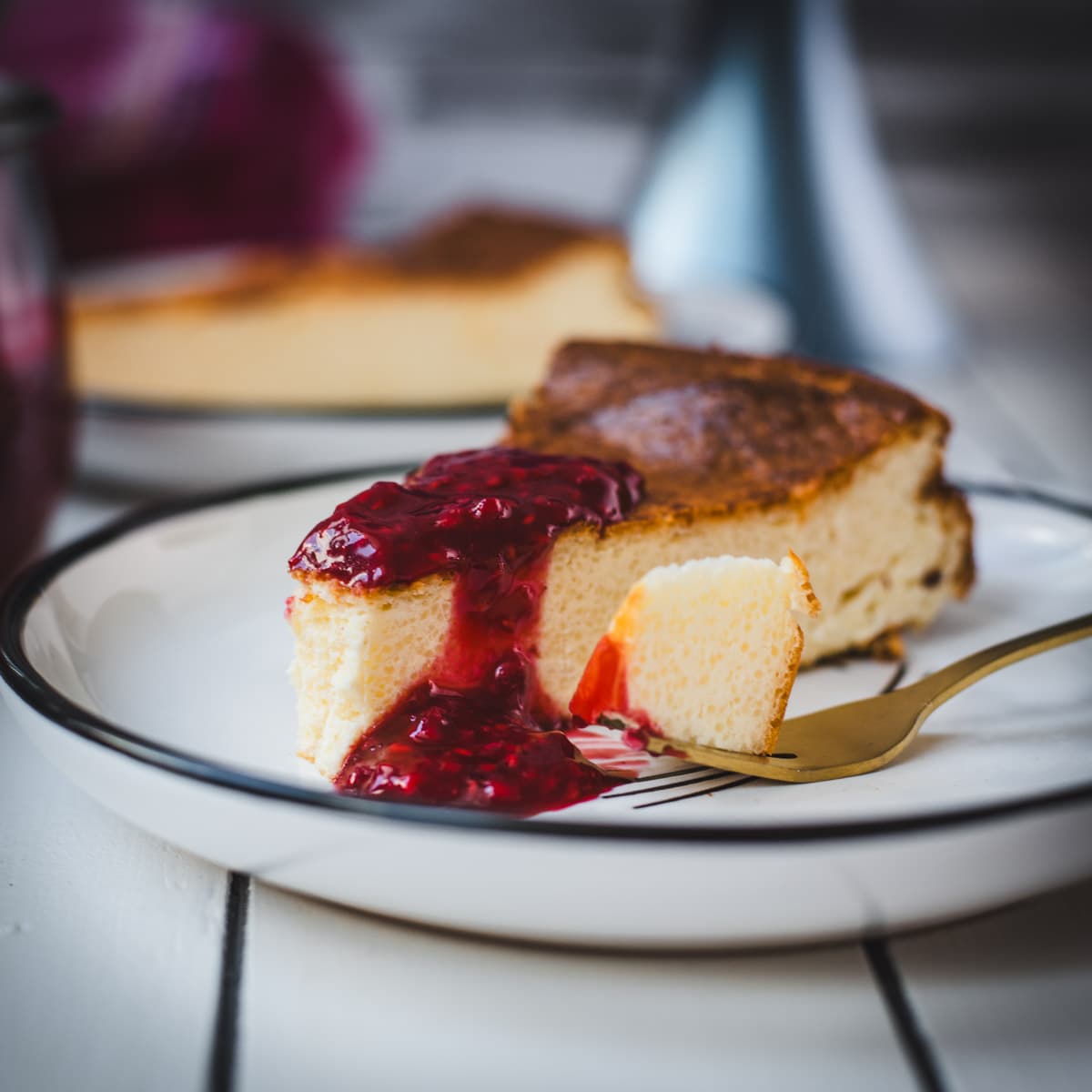 Delicious slice of semolina cheesecake with raspberry topping. Served on black and white plate.