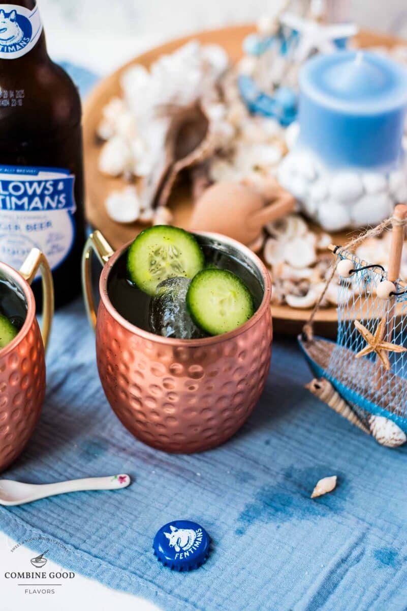 Refreshing mint cucumber Moscow mule served in copper mugs, placed on white and blue ground.