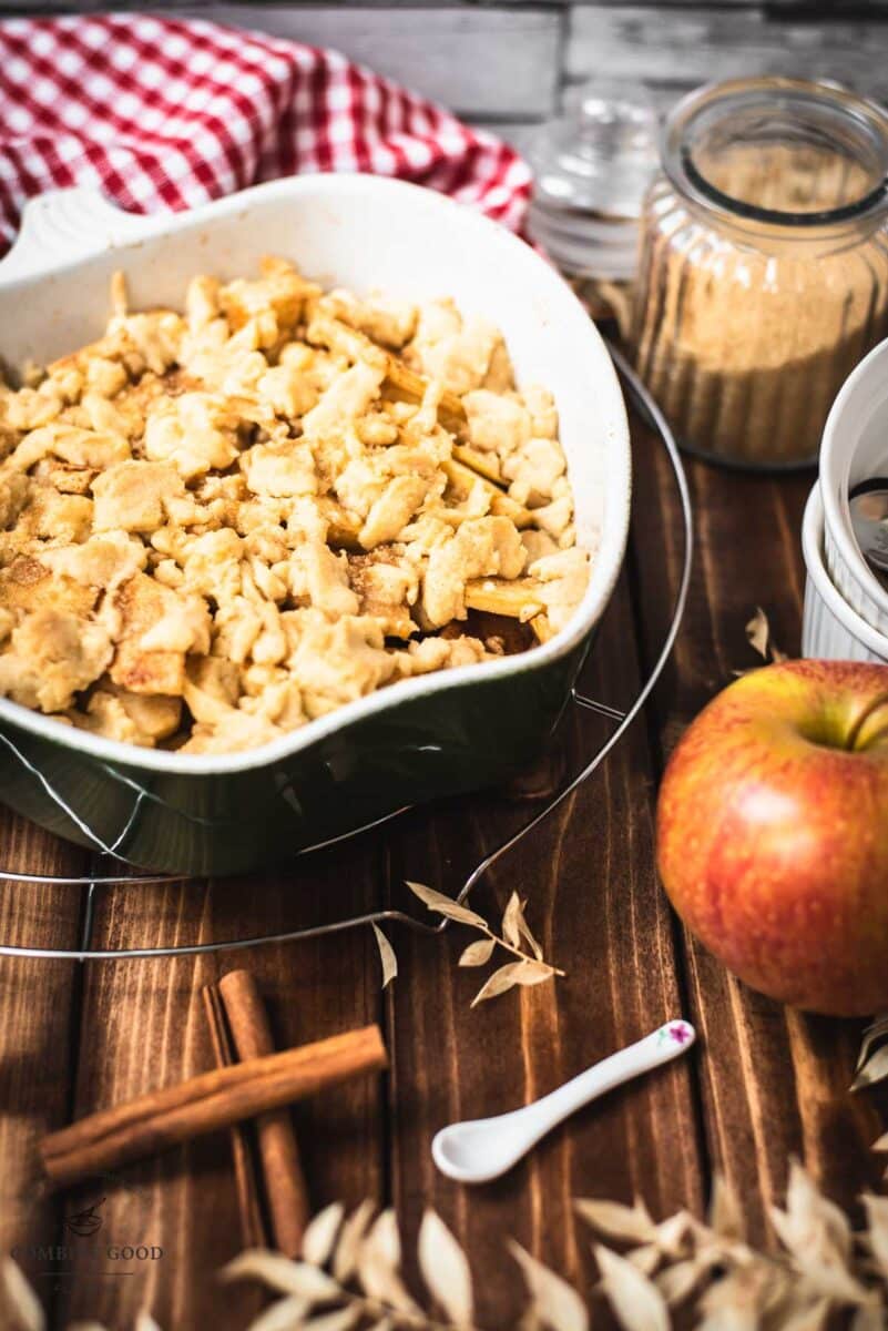 Casserole filled with freshly baked apple crisp on wooden ground.