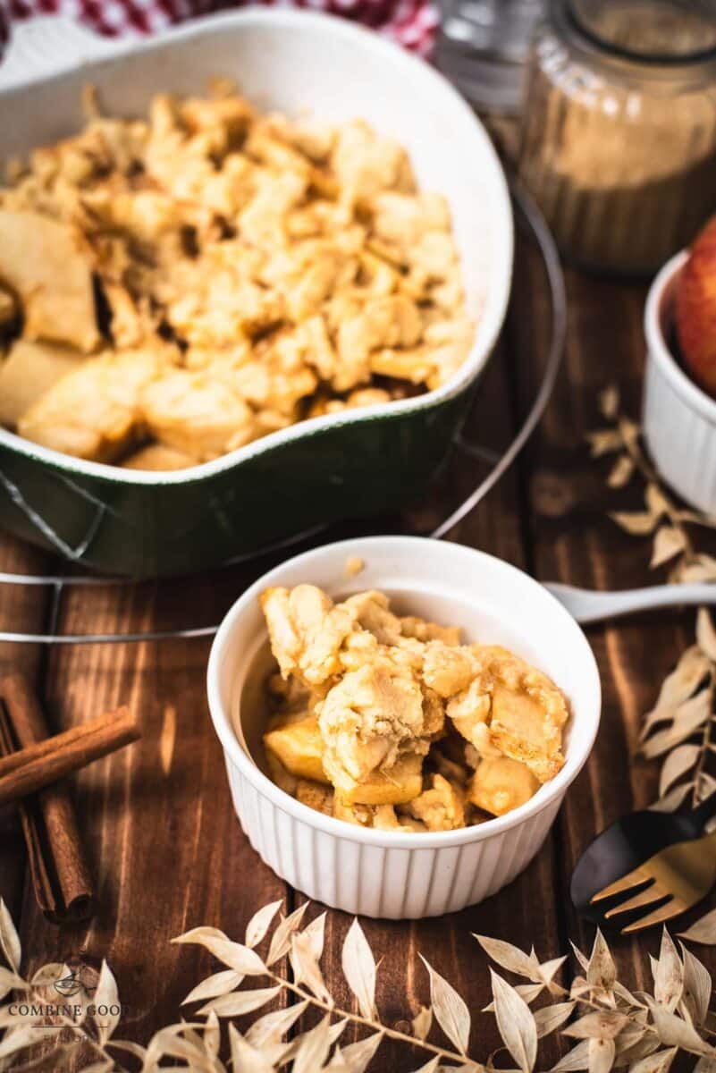 Serving bowl filled with freshly baked apple crisp on wooden ground.