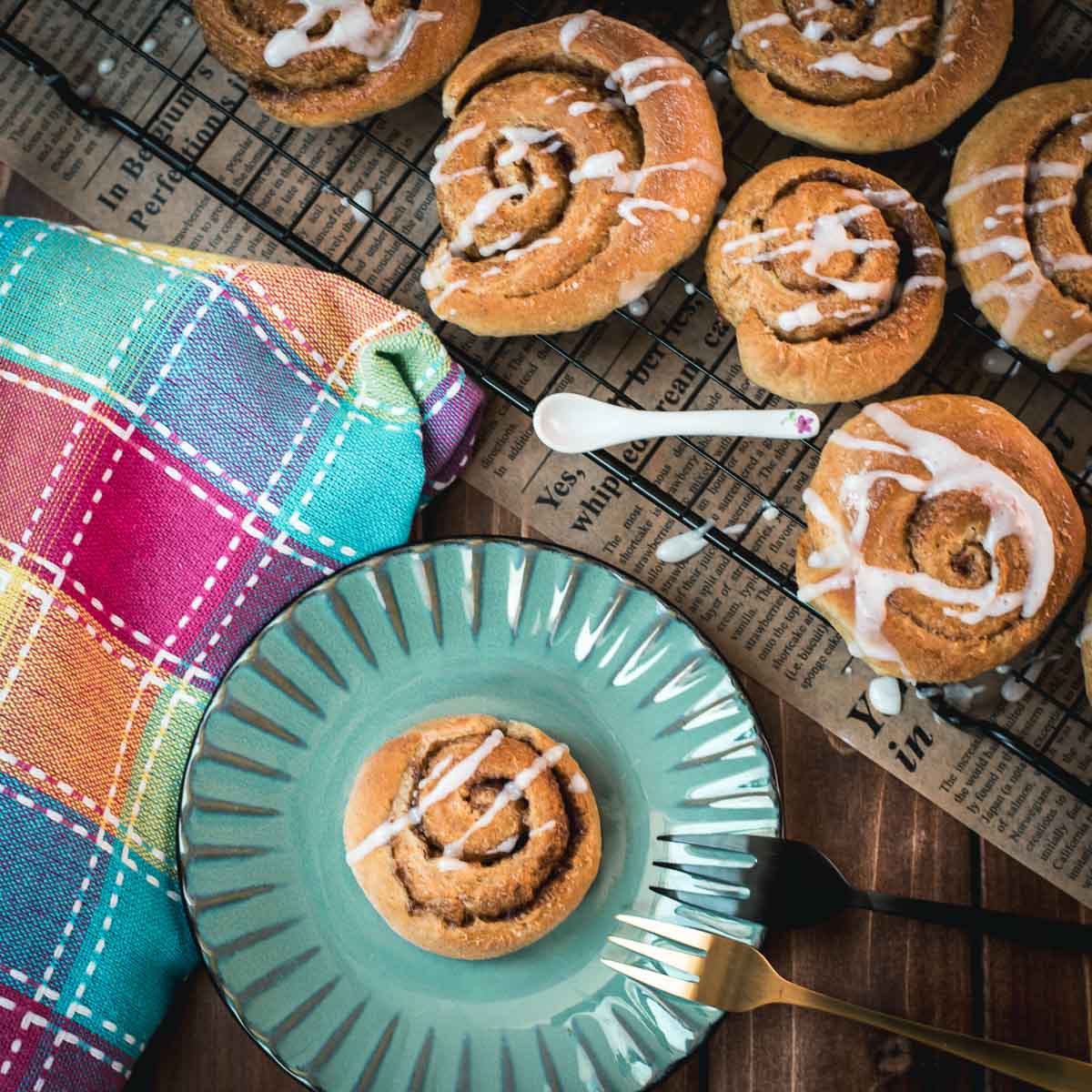 Yummy mini cinnamon rolls, drizzled with homemade sugar icing, placed on teal colored plate.