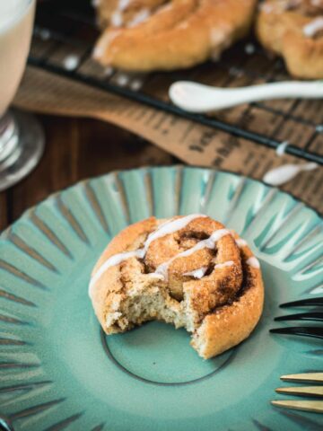 Yummy mini cinnamon rolls, drizzled with homemade sugar icing, placed on teal colored plate.