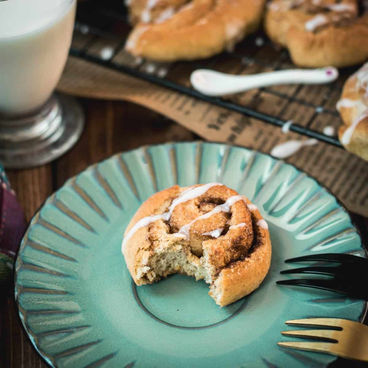 Yummy mini cinnamon rolls, drizzled with homemade sugar icing, placed on teal colored plate.