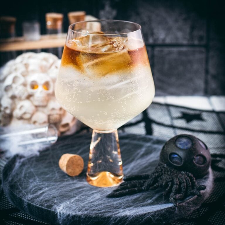 Gorgeous layered kraken ginger beer cocktail with spooky decoration.