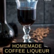 Gorgeous glass filled with homemade coffee liqueur, placed next to preserving jar and jigger.