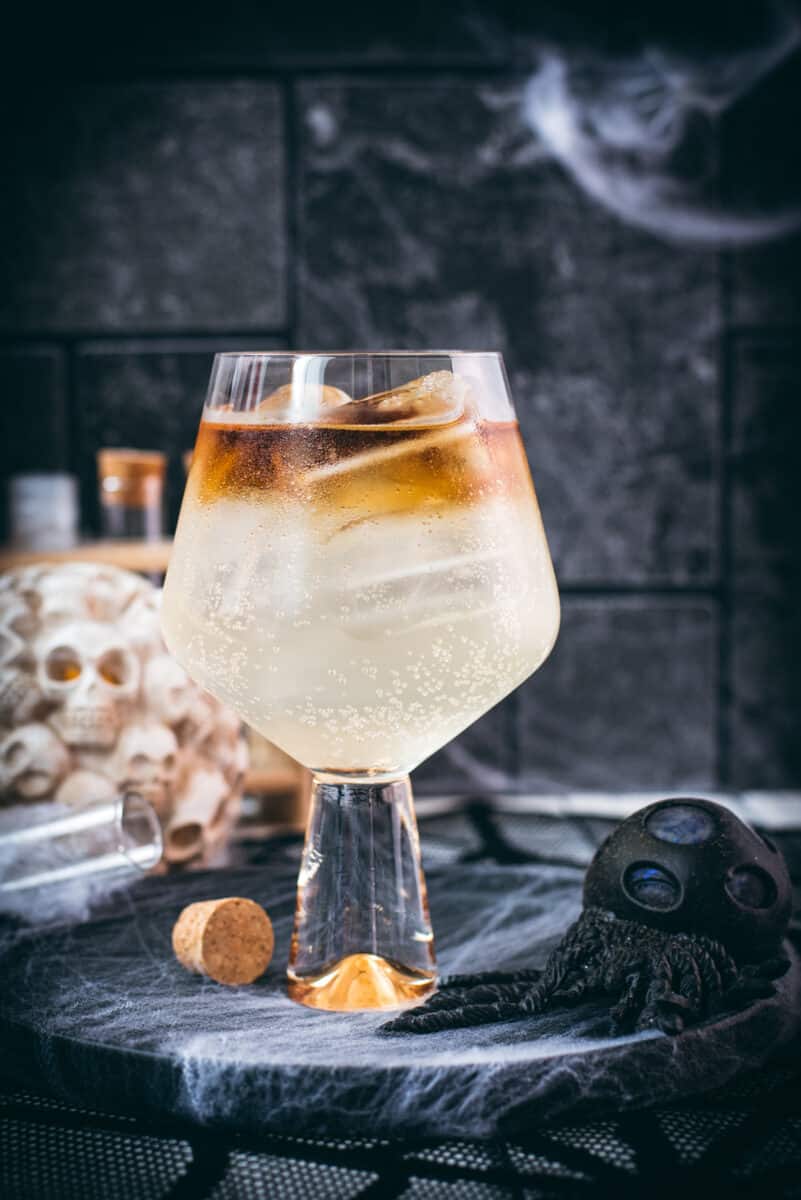 Gorgeous layered kraken ginger beer cocktail with spooky decoration.