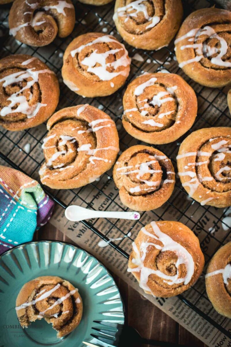 Yummy mini cinnamon rolls, drizzled with homemade sugar icing, placed on cooling rack.