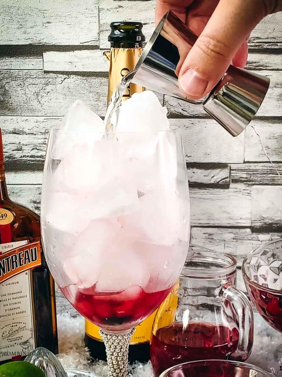 Adding Cointreau to the wine glass using a jigger.