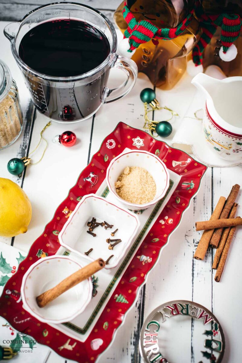 Austrian mulled wine ingredients - cinnamon stick, brown sguar, cloves, lemon, water, and red wine.