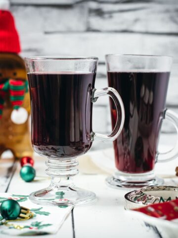 Gorgeous glasses filled with mulled placed next to Christmas decor.