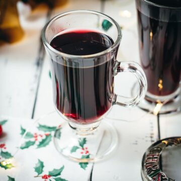 Gorgeous glasses filled with mulled placed next to Christmas decor.