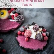 Hauntingly delicious mini Oreo tarts filled with a berry mix ganache, garnished with a creepy gummy eye, frozen berries and whipped cream. Placed on a black plate covered with spider webs.