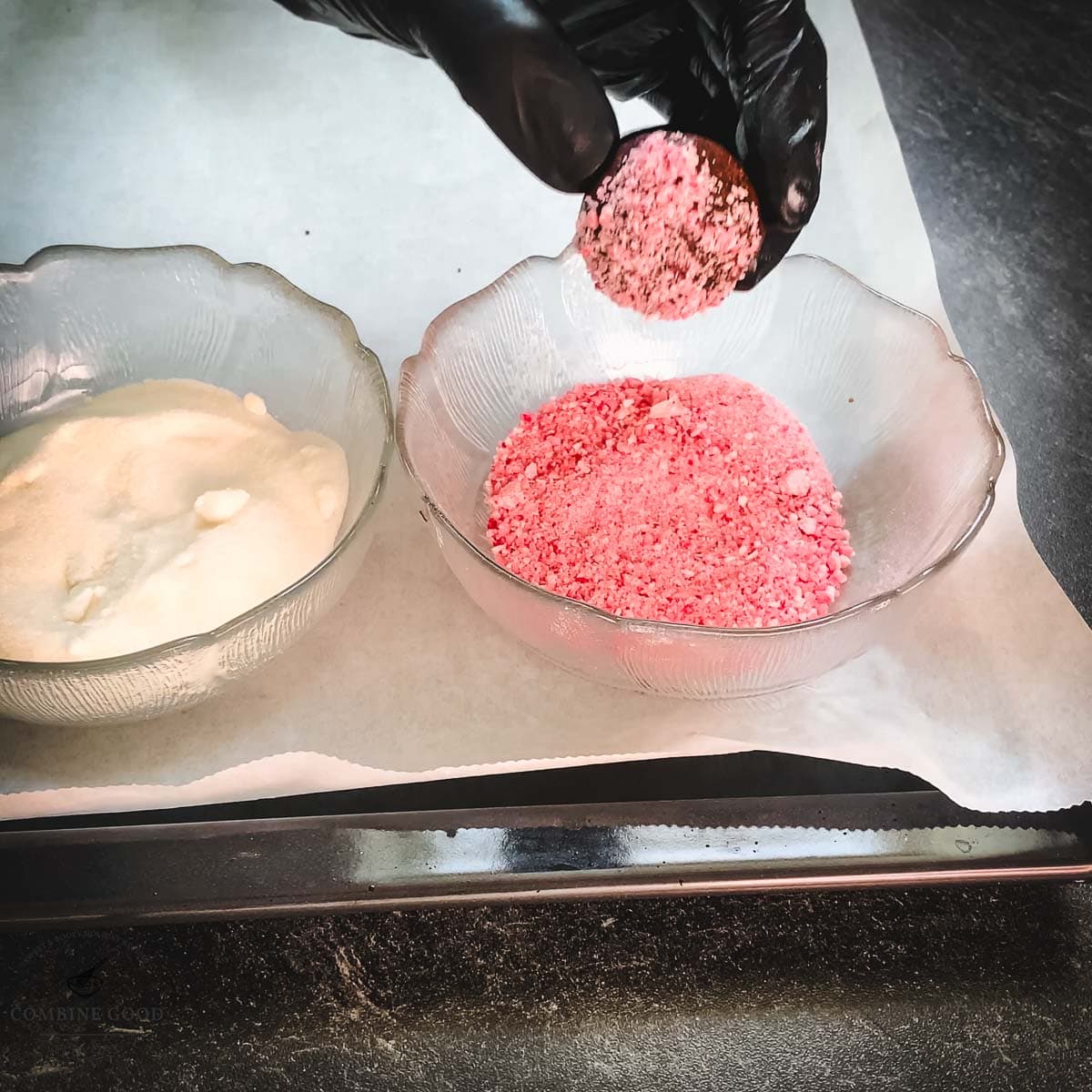 Hand with black gloves holding dough ball over a bowl filled with crushed candy canes.