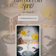 Elegant lavender gin spritz cocktail with prosecco, placed on a mirrored coaster, garnished with a lemon slice.